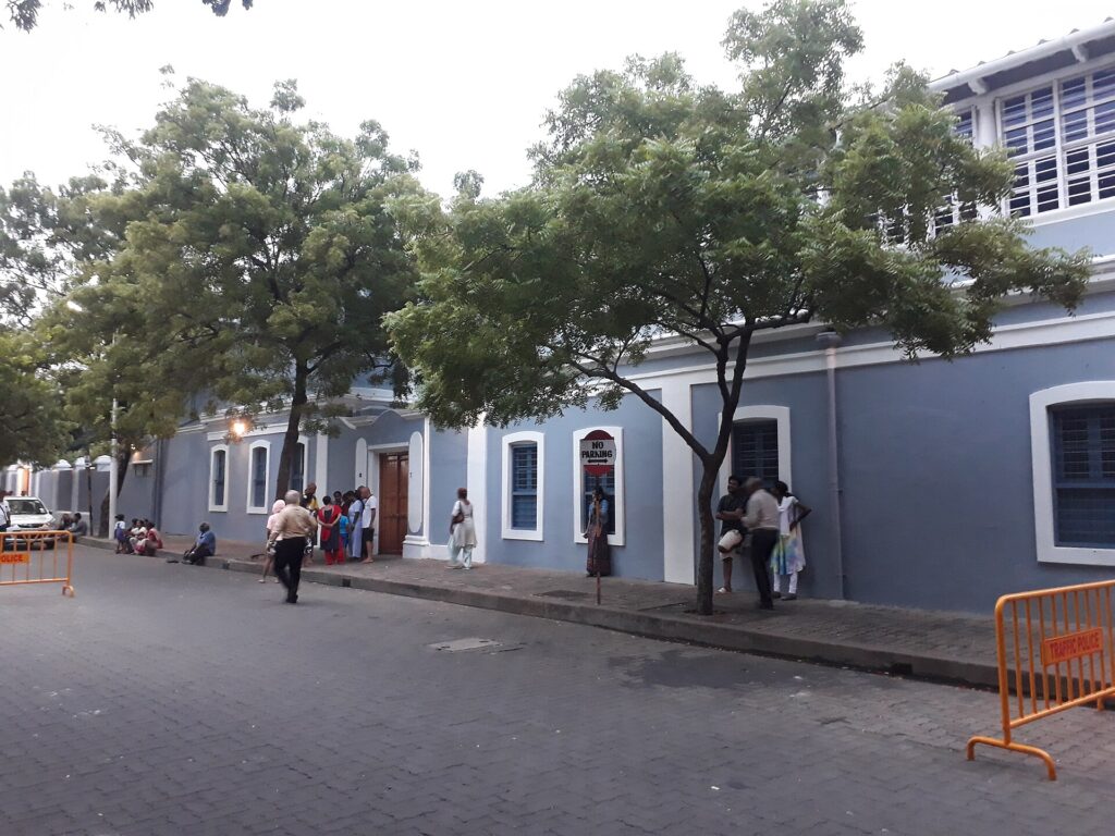 Visitors queuing along the grey Ashram buildings in White Town, the scene described in this Aurobindo Ashram visitor guide